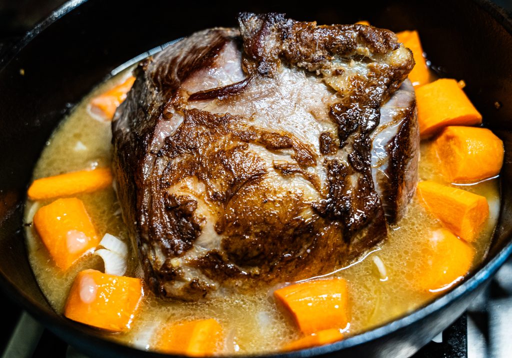 Beef shoulder roast with beef broth and carrots added, before it goes into the oven to be slow cooked